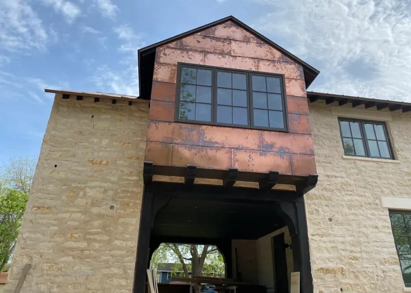 Copper metal panel facade on a stone building for Roof Repair in Todd Creek